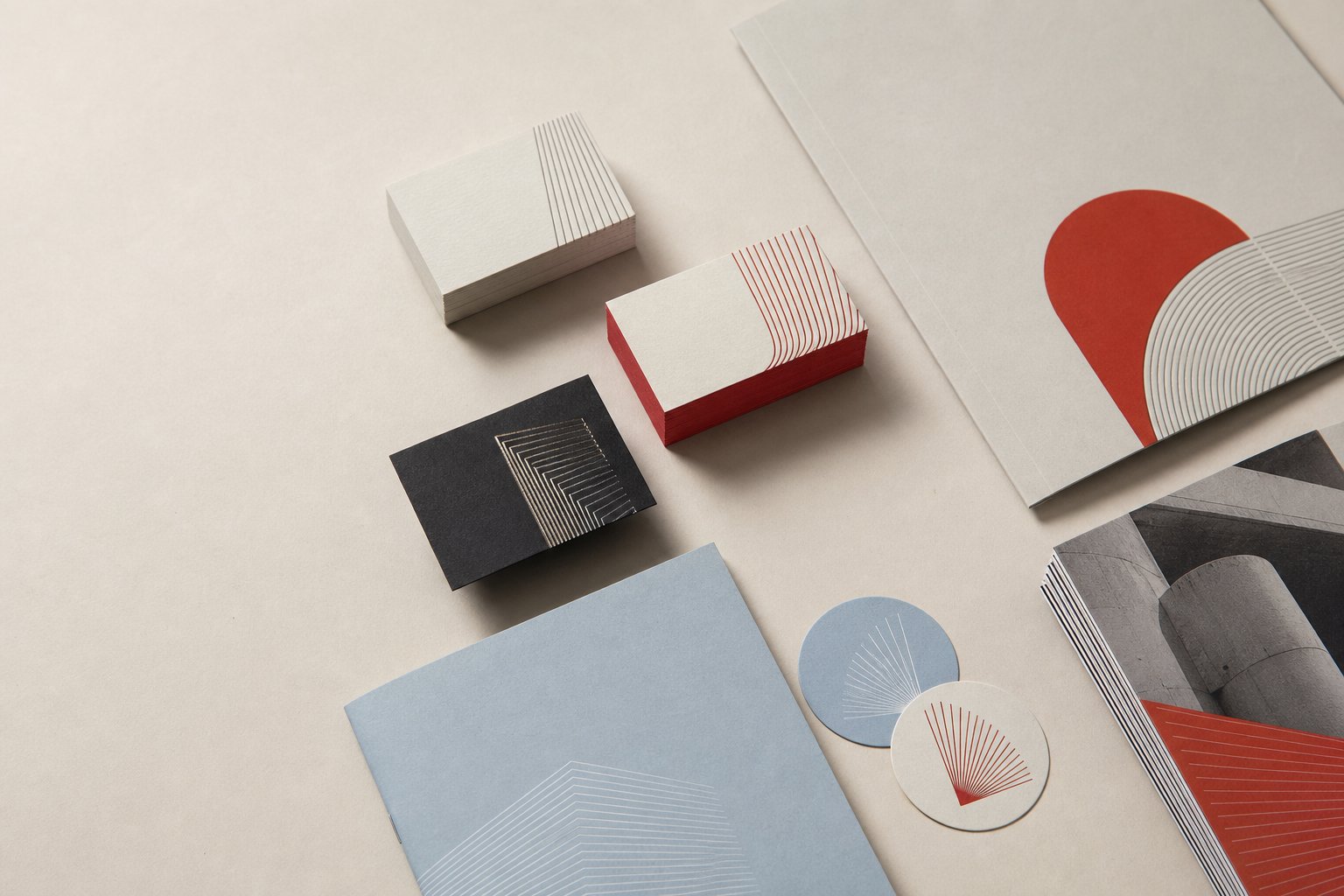 Illustrative stationery arrangement including dark business cards with metallic linework and white cards with coloured edges